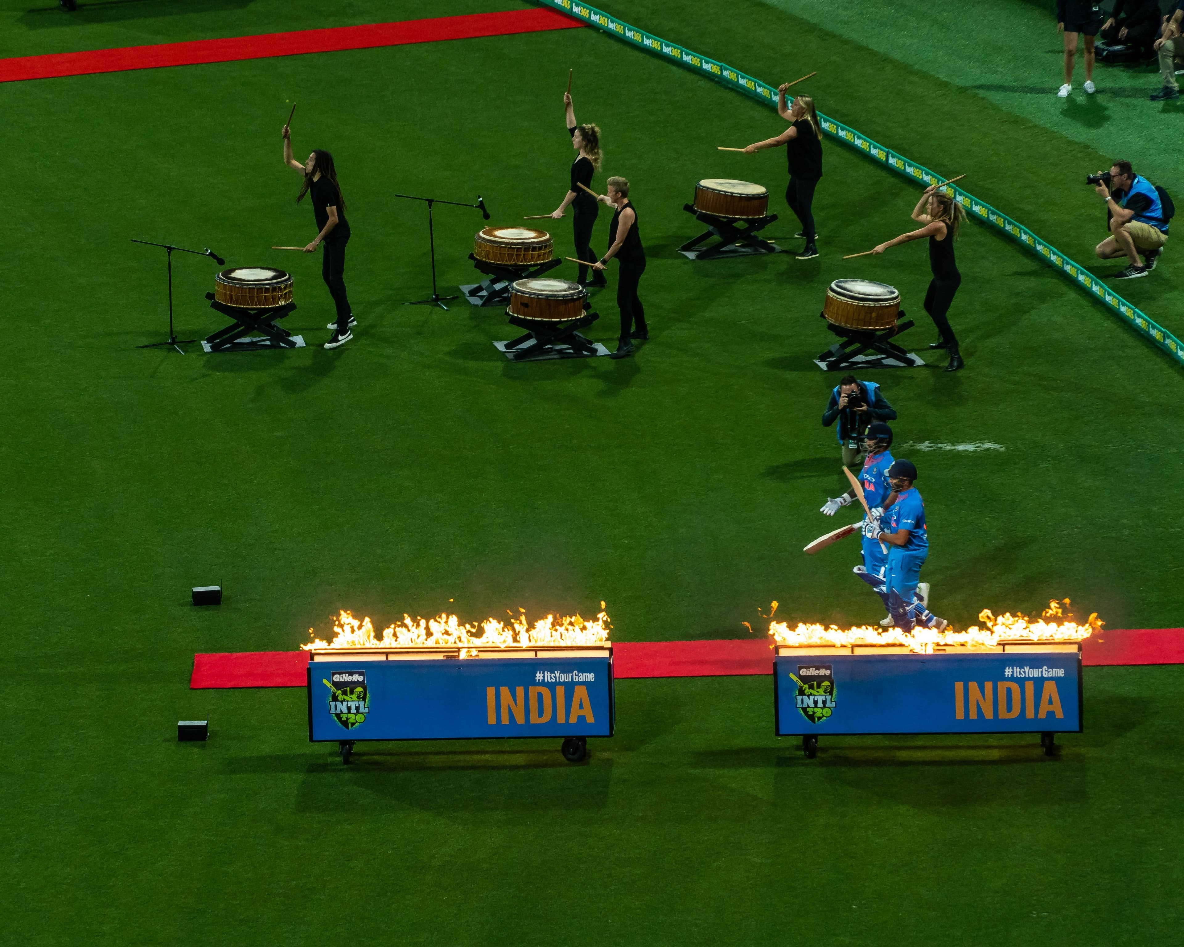 drumline band playing on cricket field with cricketers